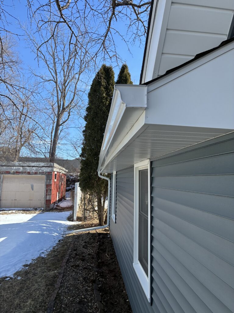 This is a photo of gutter installation in Cedar Rapids Iowa. The gutters are white and the house is gray.